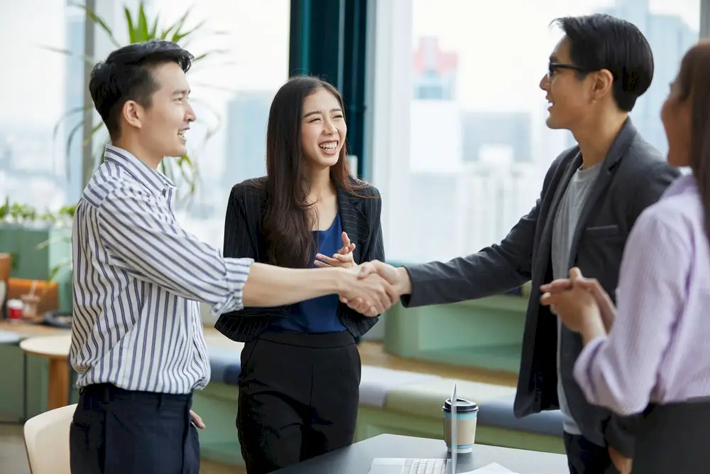 Businesspeople shake hands as part of employee recognition.