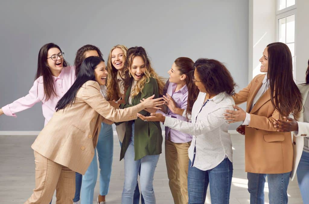 A diverse group of female employees celebrates an accomplishment at work